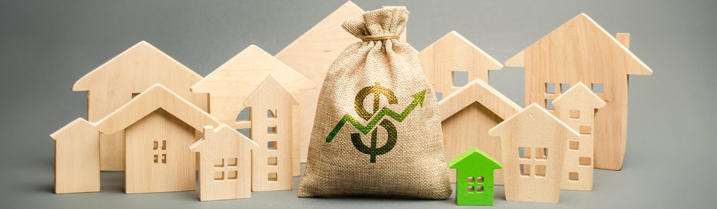 Grouping of wooden toy houses surrounding a bag featuring a dollar symbol and a green up arrow on the front.