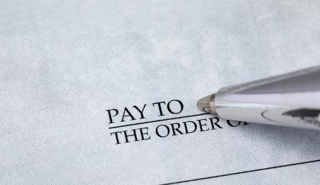 Close up of a pen getting ready to write out a check.