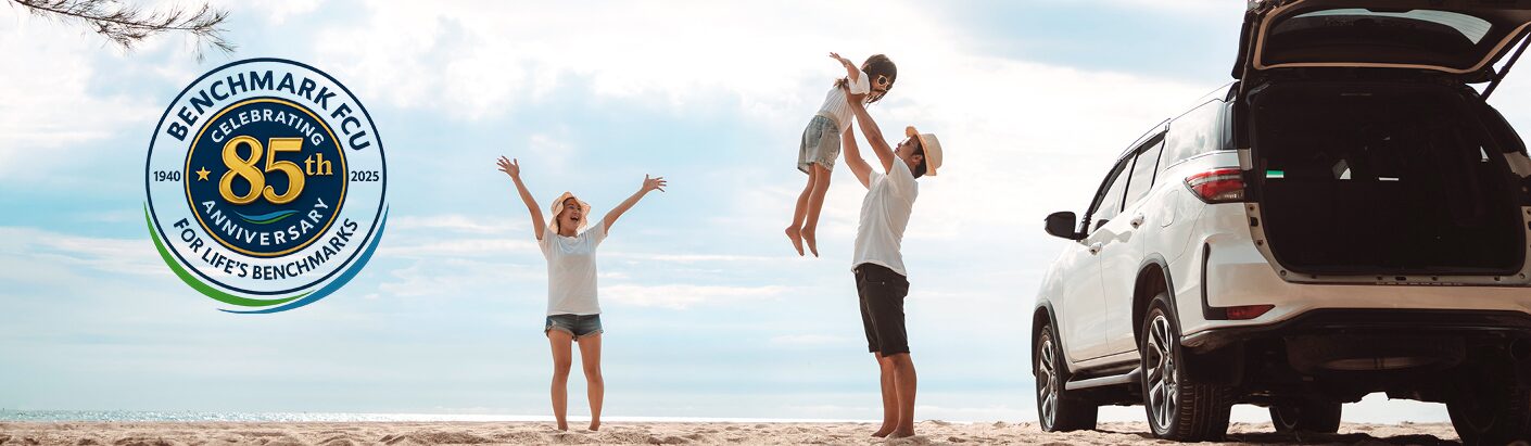 Happy family playing on the beach next to their parked SUV.